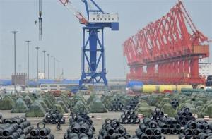 A worker rides his bicycle past piles of steel coils for export at a port in Yingkou, Liaoning province August 9, 2013. credit: Reuters/Stringer 